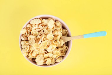 Sarı arka plan üzerinde kaşık ile kase mısır gevreği