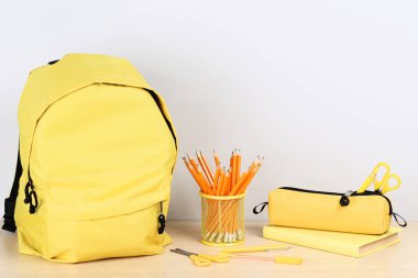 Gri arka planda okul malzemelerinin olduğu sırt çantası.