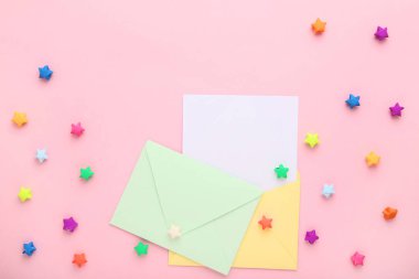 Pembe arka planda renkli kağıt yıldızlar ile zarflar