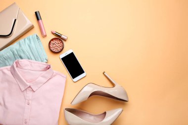 Bej b üzerinde kozmetik ve akıllı telefon ile şık kadın giysileri