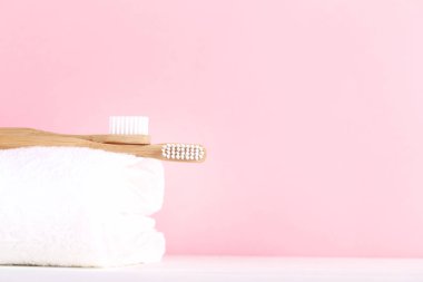 Pembe arka plan üzerinde havlu ile Bambu diş fırçaları