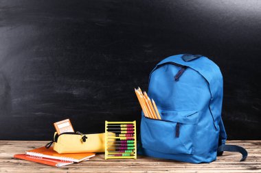 Siyah arka planda okul malzemeleriyle dolu sırt çantası.