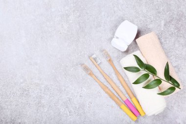 Diş ipi, havlu ve yeşil yapraklı bambu diş fırçaları