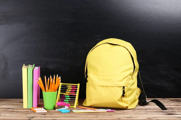 Mochila con útiles escolares sobre fondo negro —  Fotos de Stock