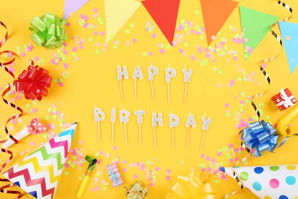 Velas de aniversário feliz com decorações de festa no backgrou amarelo — Fotografia de Stock