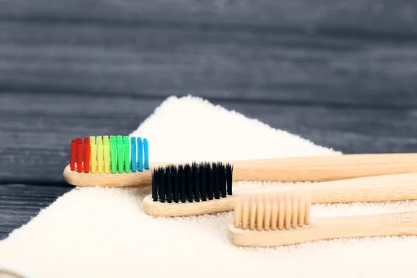 Bamboe tandenborstels met handdoek op zwarte houten tafel — Stockfoto