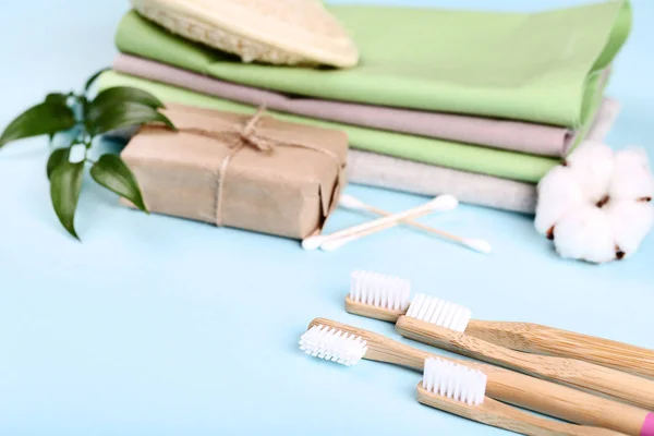 Bamboo toothbrushes with soap, cotton sticks and green leafs on blue background — Stock Photo, Image