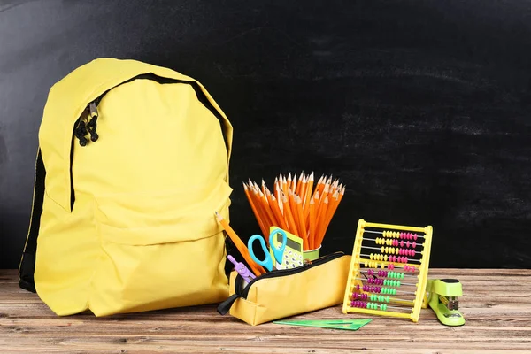 Mochila con útiles escolares sobre fondo negro —  Fotos de Stock