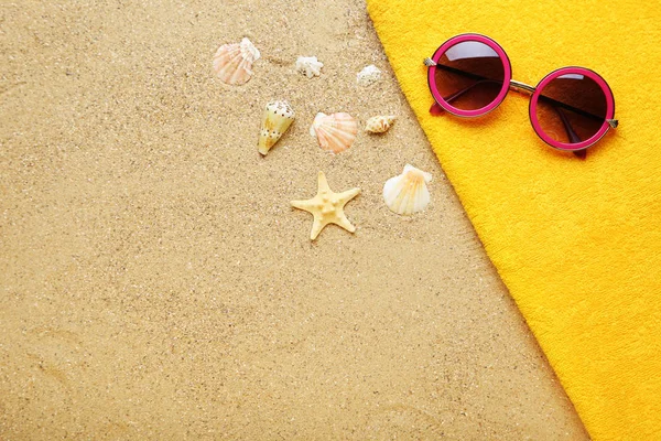 Conchas de mar con gafas de sol y toalla en arena de playa — Foto de Stock
