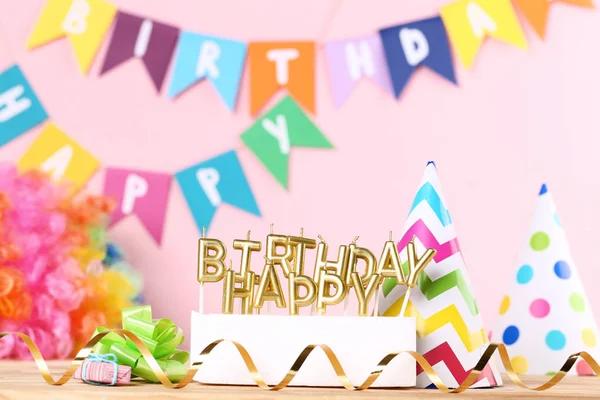 Velas de aniversário feliz com decorações de festa em fundo rosa — Fotografia de Stock