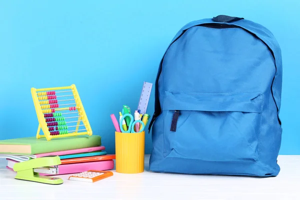 Mochila com material escolar em fundo azul — Fotografia de Stock
