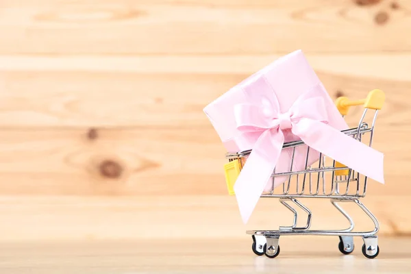 Kahverengi ahşap masa üzerinde hediye kutusu ile küçük alışveriş sepeti — Stok fotoğraf