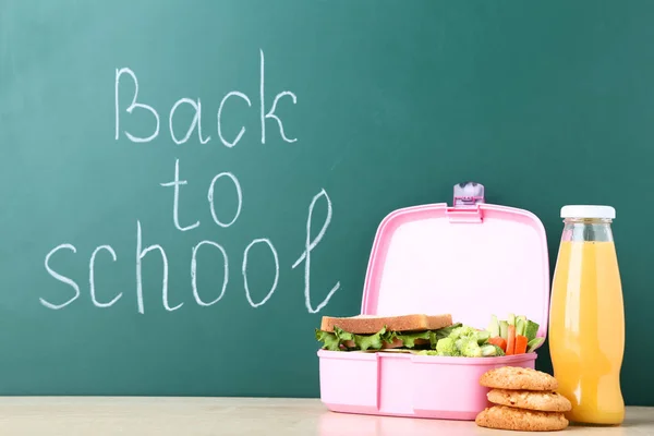 School lunch box with sandwich and inscription on chalkboard