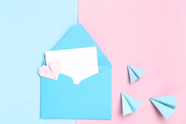 Envelope azul e aviões de papel sobre fundo colorido — Fotografia de Stock