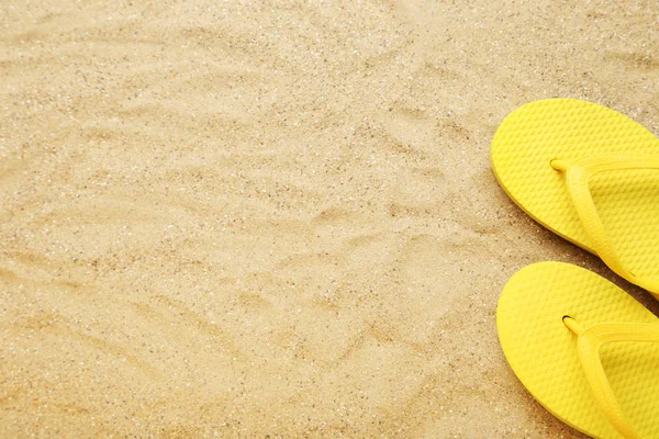 Yellow flip flops on beach sand Stock Photo