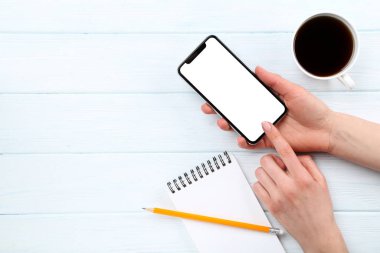 Ahşap sırt üzerinde kahve ve Not defteri bir fincan ile elle Smartphone