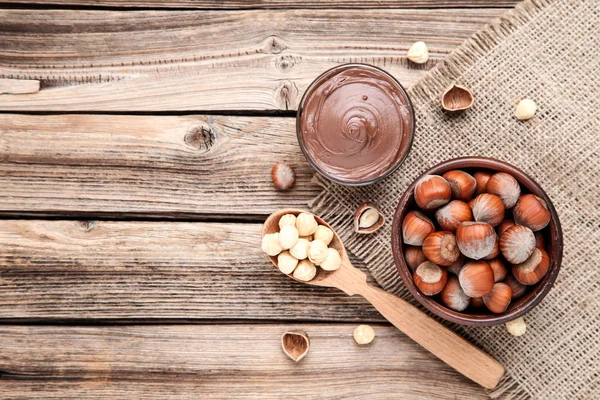 Λιωμένη σοκολάτα με φουντούκια σε καφέ ξύλινο τραπέζι — Φωτογραφία Αρχείου