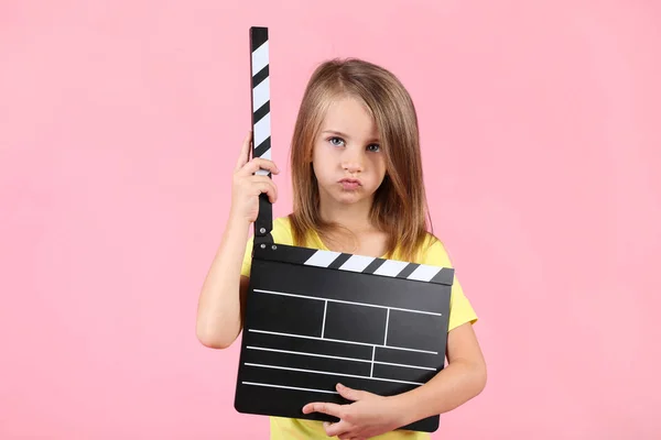 Liten flicka med Clapper ombord på rosa bakgrund — Stockfoto