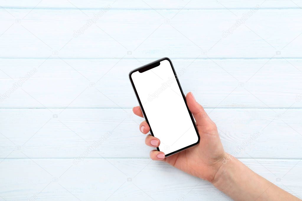 Smartphone in female hand on wooden background