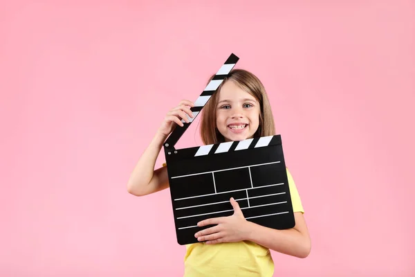 Liten flicka med Clapper ombord på rosa bakgrund — Stockfoto