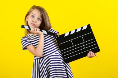 Sarı arka planda Klaket kurulu ile küçük kız