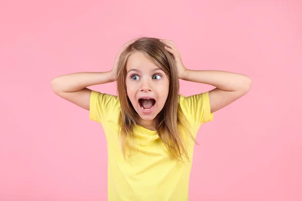 Känslomässig liten flicka på rosa bakgrund — Stockfoto