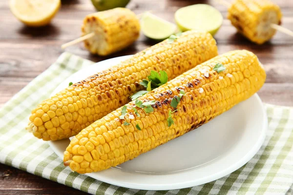 Grilled corn with green parsley leafs on brown wooden table — Stock Photo, Image