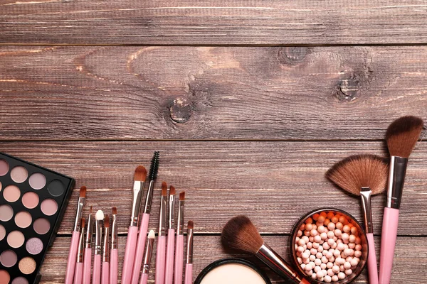 Make-up borstels met palet op bruin houten tafel — Stockfoto