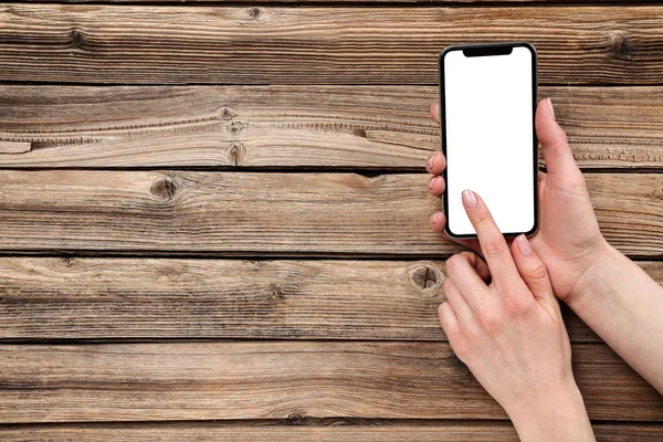 Смартфон в женских руках на деревянном фоне — стоковое фото