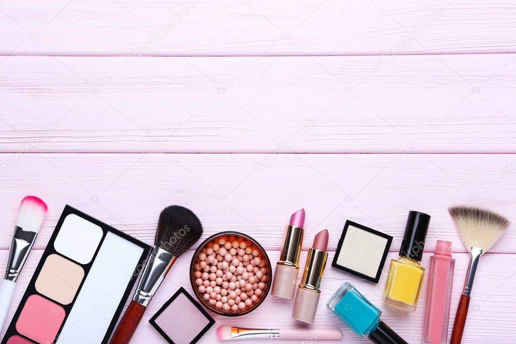 Different makeup cosmetics on pink wooden table