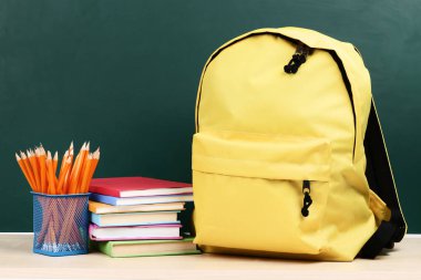 Yeşil arka plan üzerinde kitap ve kalem ile Sırt Çantası