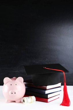 Piggybank mezuniyet kapağı ve kara tahta üzerinde dolar banknotlar ile