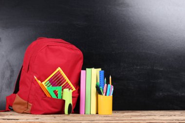 Siyah arka planda okul malzemeleriyle dolu sırt çantası.