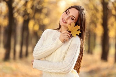 Kuru akçaağaç tutan güzel kadın sonbahar parkta yapraklar