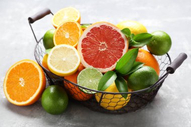 Gri ahşap masa üzerinde sepet yeşil yapraklı narenciye