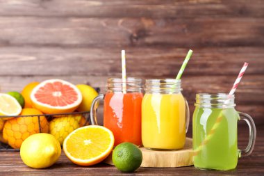 Ahşap masa üzerinde meyve ile cam kavanozlara narenciye suyu