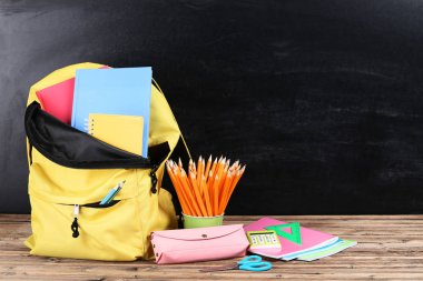 Siyah arka planda okul malzemeleriyle dolu sırt çantası.