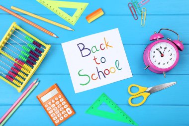 Mavi ahşap masa üzerinde kırtasiye ile Okula Metin Geri