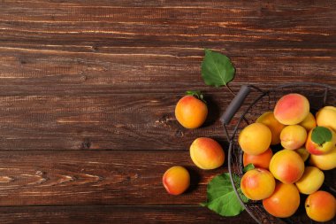 Kahverengi ahşap masa üzerinde sepet içinde tatlı kayısı