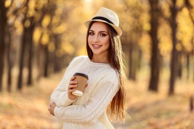 Şapka ve kağıt Kupası Sonbahar Park ile güzel kadın