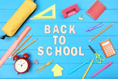 Mavi ahşap masa üzerinde kırtasiye ile Okula Metin Geri