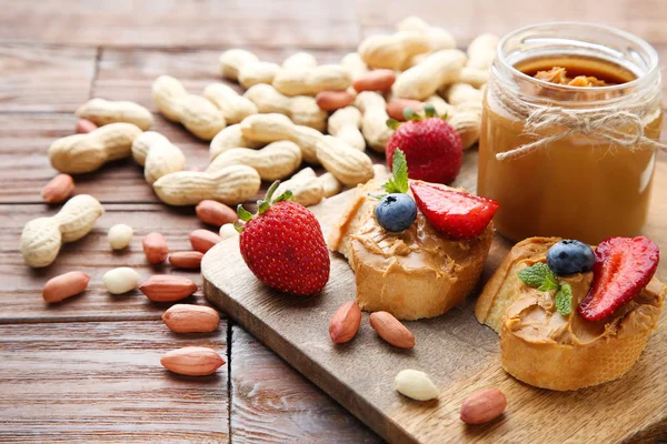Хлеб с арахисовым маслом, фрукты и орехи на деревянном столе — стоковое фото
