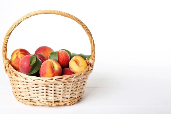 Fresh peaches in basket on white wooden table — Stock Photo, Image