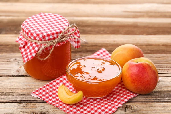 Marillenmarmelade in Schüssel und Glas auf braunem Holztisch — Stockfoto