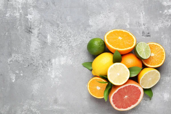 Citrus fruits with green leafs on grey wooden table — Stock Photo, Image