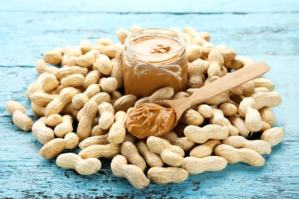 Erdnussbutter und Nüsse auf blauem Holztisch — Stockfoto