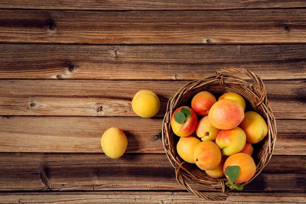 Солодкі абрикоси в кошику на коричневому дерев'яному столі — стокове фото