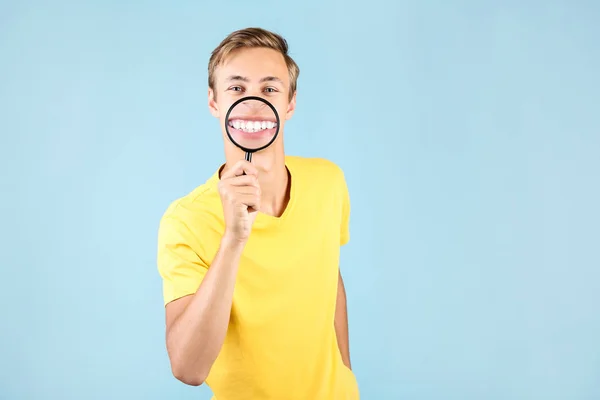 Ung man med förstoringsglas på blå bakgrund — Stockfoto