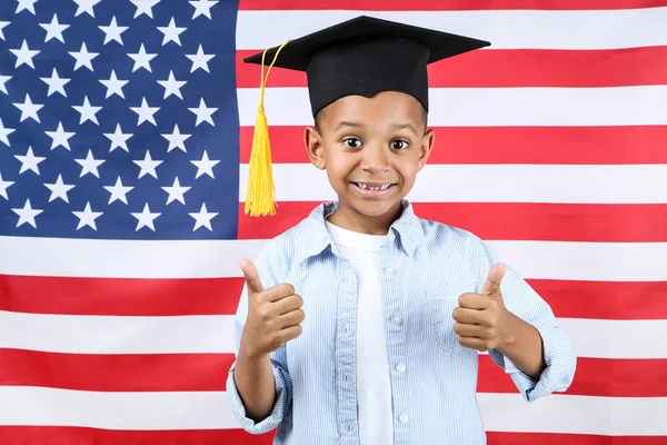 Lindo chico en gorra de graduación en fondo de bandera americana — Foto de Stock
