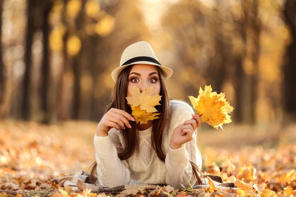 Mooie vrouw met Maple Leafs liggend op de grond in de herfst p — Stockfoto